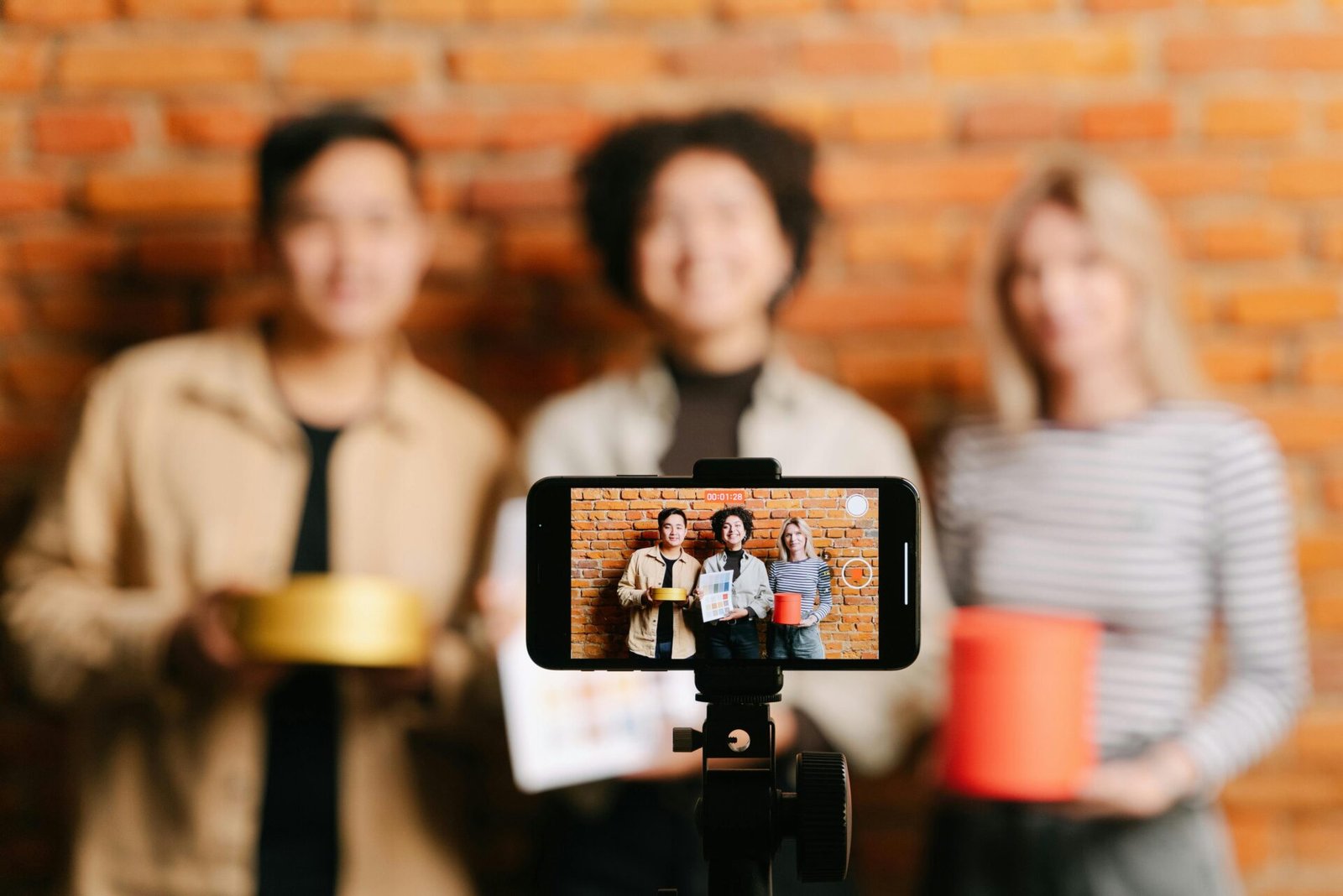 Câmera de smartphone gravando creators em cenário de fundo de tijolos.